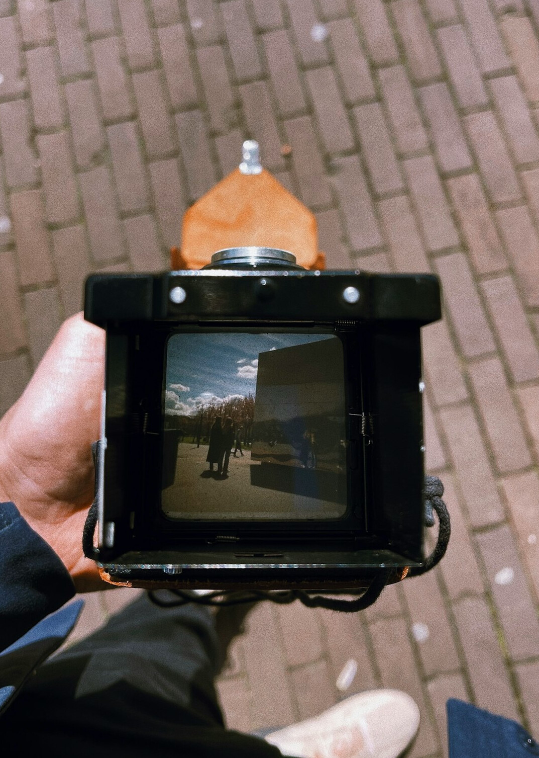 Close-up of a vintage camera lens held by a photographer on a city street